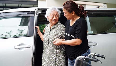 Caregiver help Asian elderly woman disability patient get in her car, medical concept.