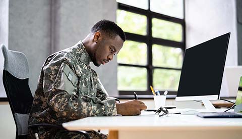 Veteran African Man Person Education. Army Soldier, at desk working.