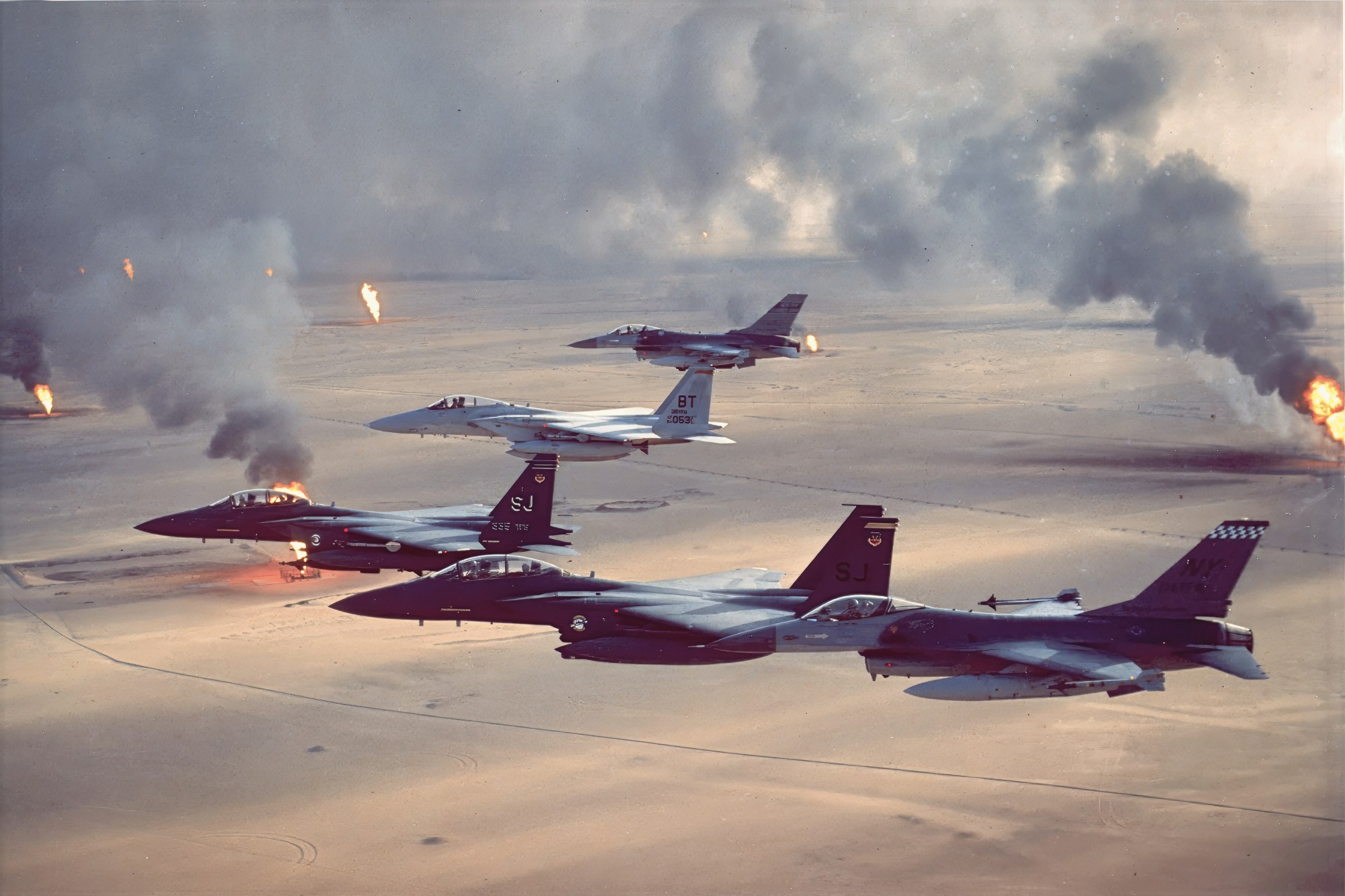 F-16A Fighting Falcon, F-15C Eagle and F-15E Strike Eagle fighter aircraft fly over burning oil field sites in Kuwait during Operation Desert Storm