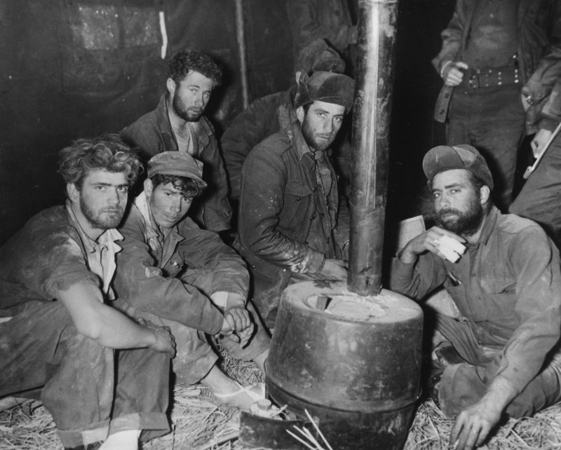 Recently returned American and Australian prisoners huddle close to a stove at a U.S. Army medical clearing station in Korea, February 10, 1951. Studies conducted in the 1950s and afterwards found that former prisoners developed disabilities at a much higher rate than others who served in the same conflict. (National Archives)
