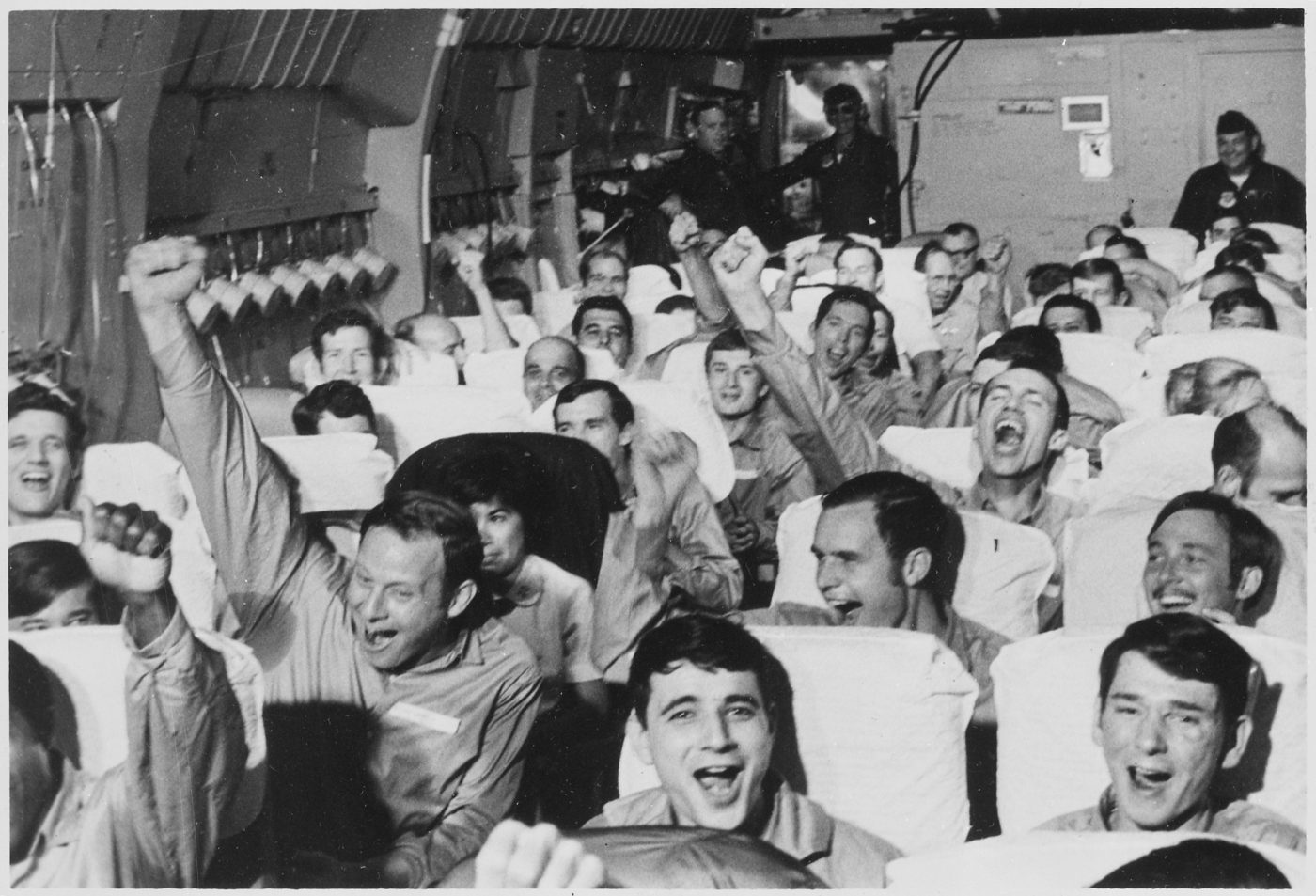 Americans raise their arms in jubilation as their military transport takes off from Hanoi on March 28, 1973, following their release from captivity at the end of the Vietnam War. During and after the war, Congress made it easier for former prisoners to qualify for compensation and medical treatment. (National Archives).