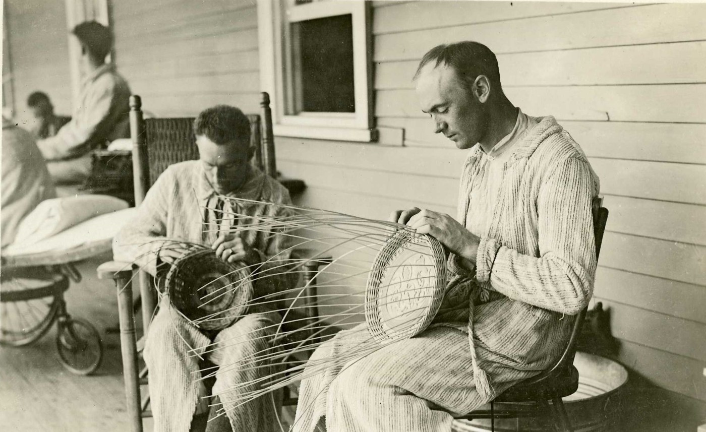 Recuperating soldiers weave baskets on the porch at Walter Reed General Hospital in Washington, D.C., c. 1918. Arts and crafts activities helped patients improve their fine motor skills and powers of concentration. (National Museum of Health and Medicine)