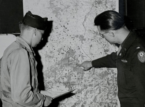 Photograph of European officer pointing to a map of isolated burials to be exhumed for repatriation, c. 1946.; (NARA).