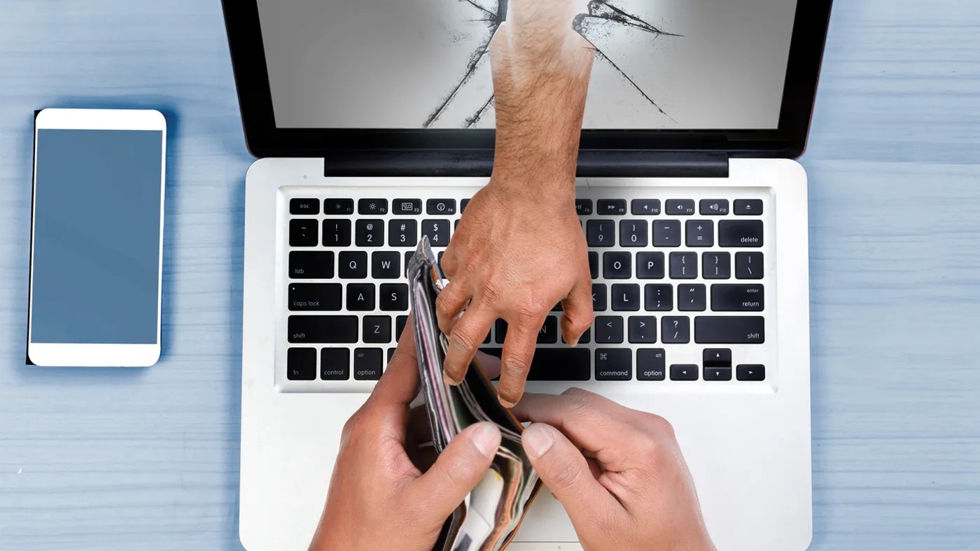 Identity Theft VA News thumbnail, an overview of a laptop with the user holding their wallet and another hand from behind the laptop reaching over to grab the user's wallet