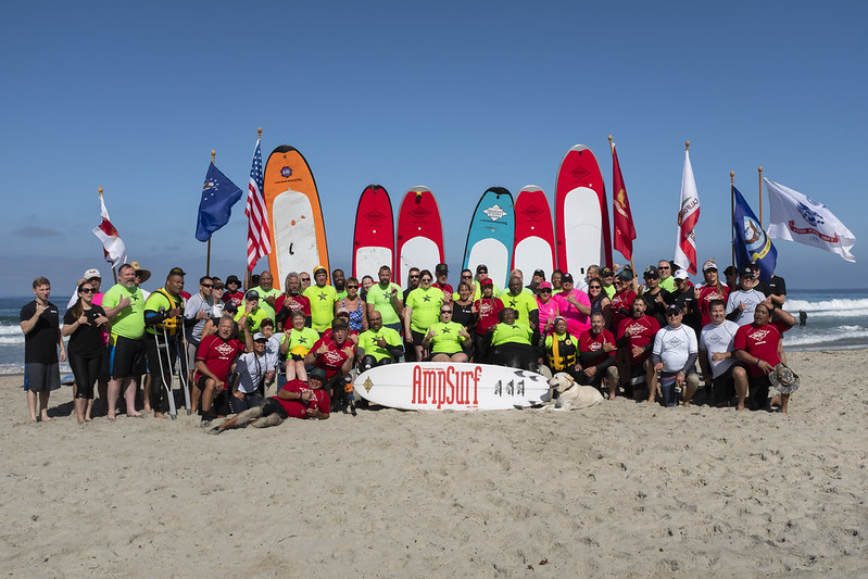 Veterans standing on the beach for a group photo with surfing equipment