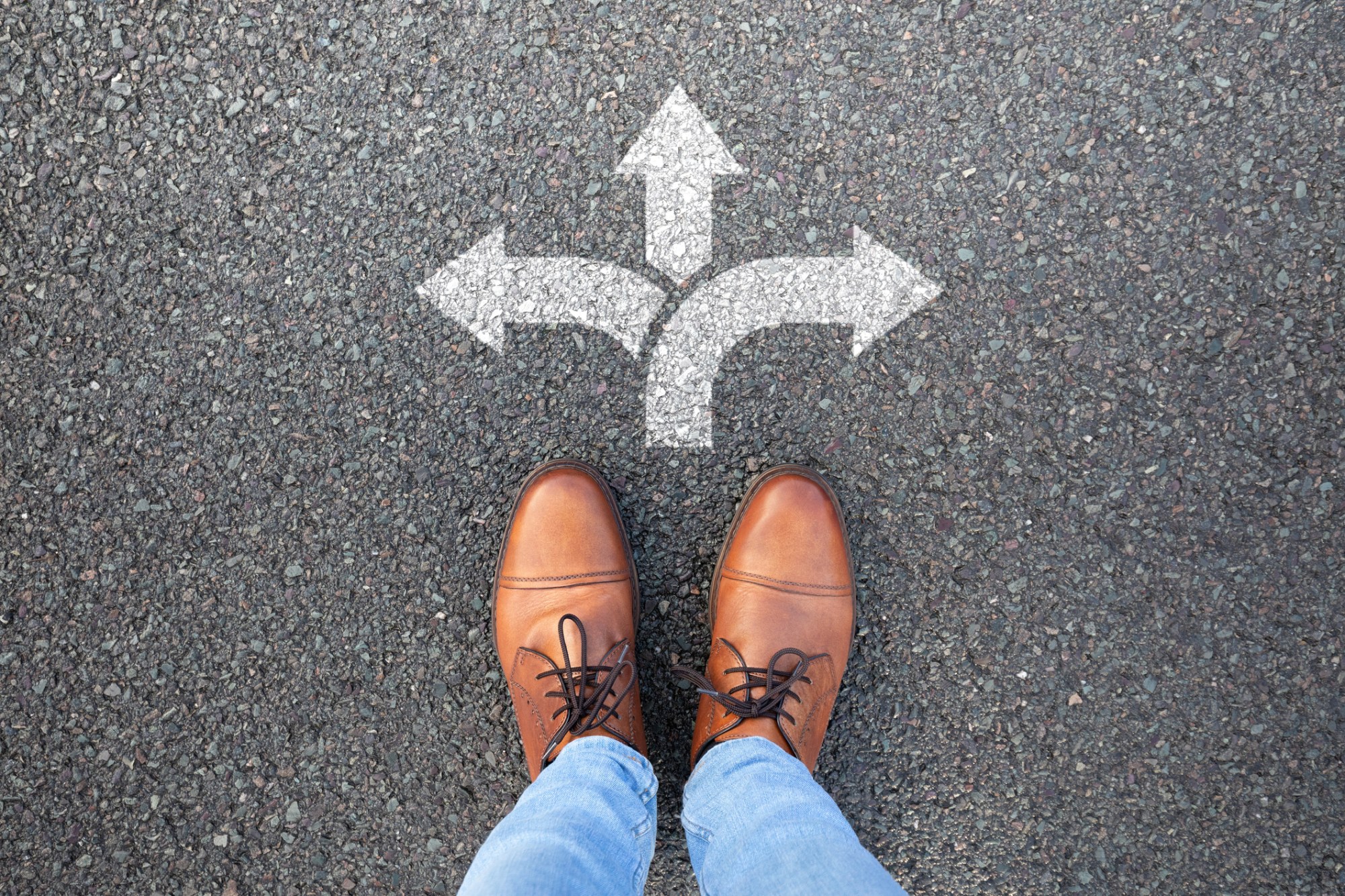 A person's shoes are shown on pavement with arrows pointing to 3 different paths a person could take.