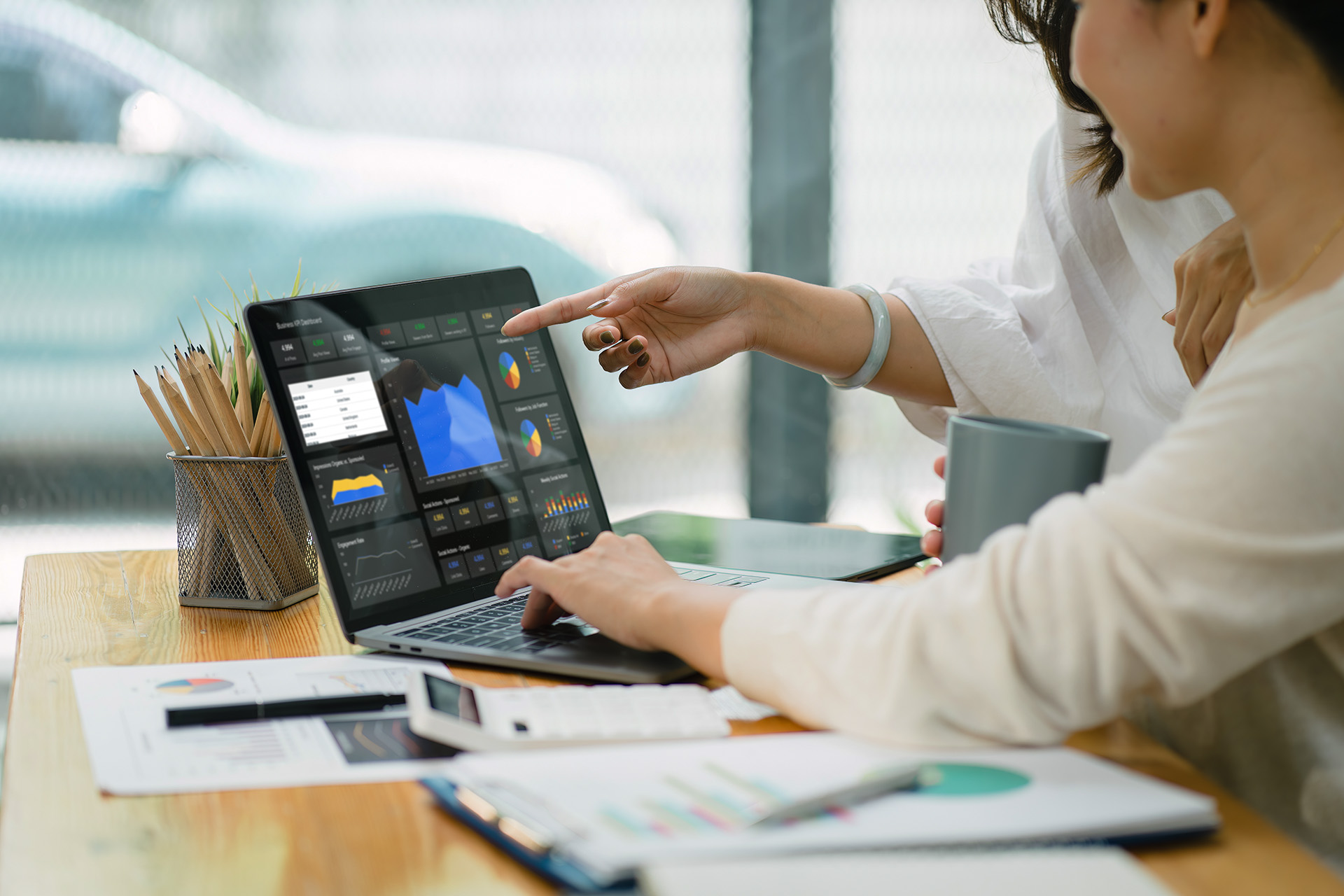 Businesswoman advisor team are analyzing data charts, graphs, and a dashboard on a laptop screen in order to prepare a statistical report and discuss financial data in an office.